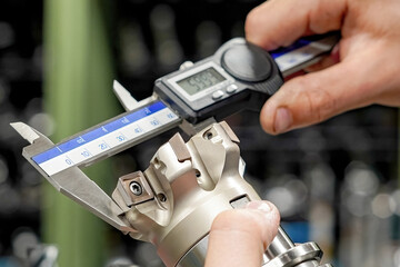 The worker operator of the cnc machine tool measures the cutting tool with a caliper for further work on milling and turning machines.