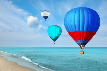Fototapeta na wymiar Bright hot air balloons flying over blue sea