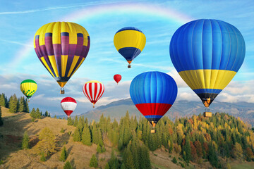 Fototapeta premium Bright hot air balloons flying in sky with rainbow over mountain