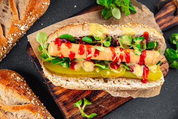 Hot Dog sausage bun, tomato sauce, pickled cucumber, green lettuce leaf takeaway food tasty fresh eating appetizer meal food snack on the table copy space