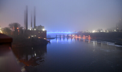 Illuminated highway road bridge across the river in fog