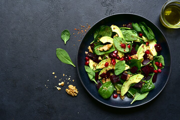 Spinach salad with avocado, beet root, walnuts and pomegranate seeds. To view with copy space.