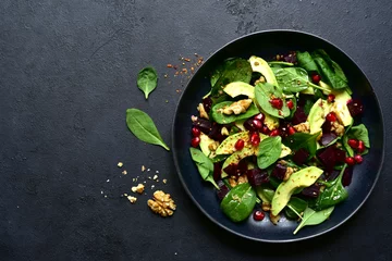 Poster Spinach salad with avocado, beet root, walnuts and pomegranate seeds. To view with copy space. © lilechka75