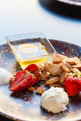 Fragole fresche con pallina di gelato, biscotti sbriciolati e uovo crudo su un piatto colorato,...