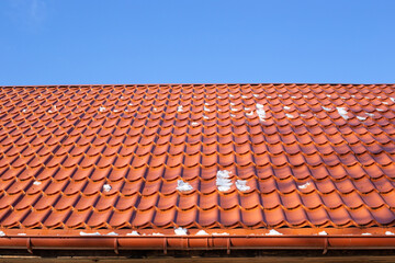 roof made of metal tiles on a winter sunny day with remnants of snow. Roof cleaning.