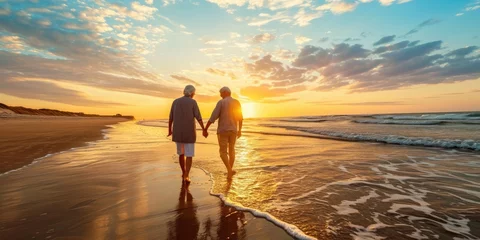 Foto auf Acrylglas Sonnenuntergang am Strand A joyful elderly couple walking on the beach enjoying a leisurely sunset