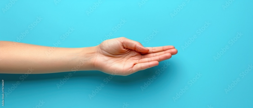 Poster a person's hand on a blue surface with a small object in the middle of the image and a small object 