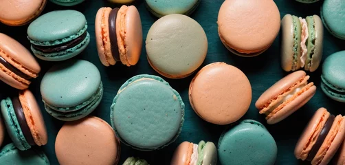 Rollo Macarons  a group of macaroons sitting next to each other on top of a blue tablecloth covered in green and orange macaroni and white macaroons.