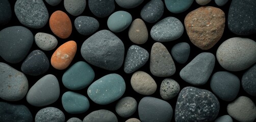  a close up of a bunch of rocks with one orange and one gray rock on top of the rocks and on the bottom of the rocks is a black background.