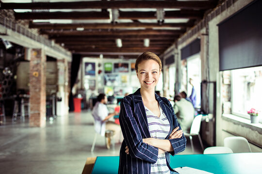 Portrait of a smiling young businesswoman in busy office