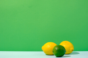 Lemons and lime citrus fruit against a green and blue colored background