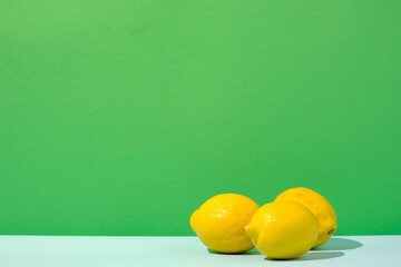 Three lemons citrus fruit against a green and blue colored background