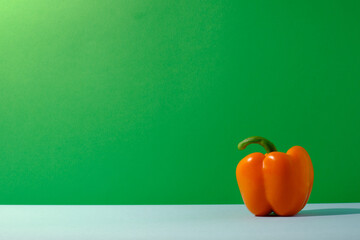 Orange bell pepper against green and blue colored background