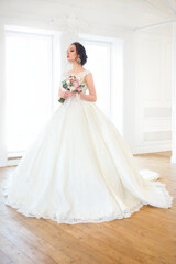 Beautiful brunette woman with bouquet posing in a wedding dress