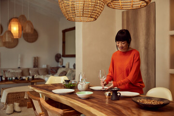 A lovely Asian woman serving dinner for her friends, at home.