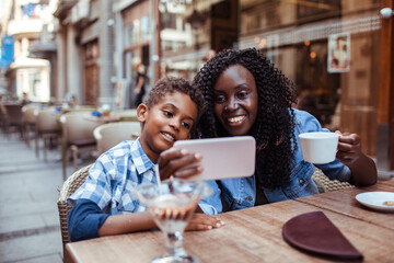 Mother and Son Enjoying a Video Call at an Outdoor Cafe