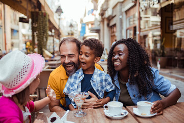 Multicultural family enjoying desserts at an outdoor cafe