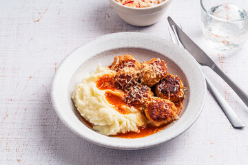 Mashed potatoes with meatballs in tomato sauce, celeric and apple salad on white background