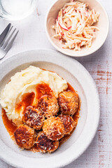 Mashed potatoes with meatballs in tomato sauce, celeric and apple salad on white background