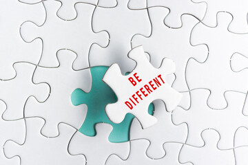 Fototapeta premium Be different text on Jigsaw Puzzle over green background.