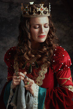 sad medieval queen in red dress with handkerchief and crown