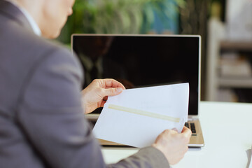 Seen from behind woman worker in green office opening letter