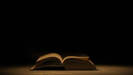 Studio shot of old retro hardcover book on dark background in warm light. Old vintage book laying...