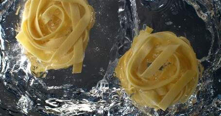 Super slow motion of italian pasta is falling in pot with boiling water to be cooked with traditional recipes for dish preparation by chef in restaurant kitchen at 1000 fps.