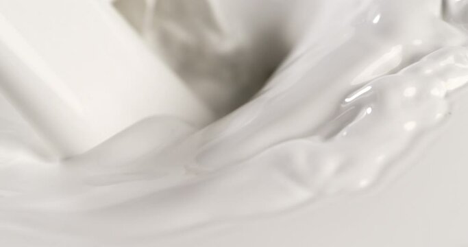 Super slow motion macro of fresh organic bio milk is being poured with splashing white drops in dairy farm at 1000 fps.
