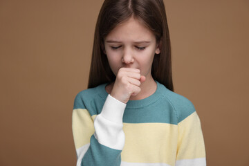 Sick girl coughing on brown background. Cold symptoms