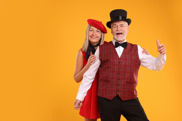 Portrait of senior couple on orange background, space for text