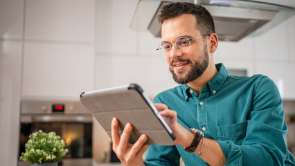 One young adult caucasian man work use digital tablet online at home