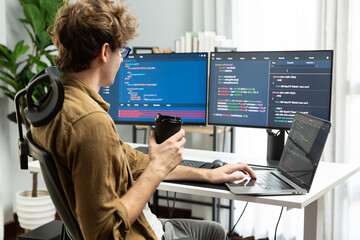 Working IT developer holding coffee cup with looking online software on pc at modern office on...