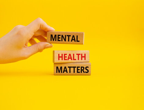 Mental Health Matters symbol. Concept words Mental Health Matters on wooden blocks. Beautiful yellow background. Doctor hand. Healthcare and Mental Health Matters concept. Copy space.