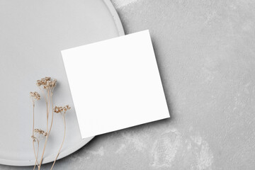 Stylish square blank card mockup with botanical decor and copy space on grey concrete background