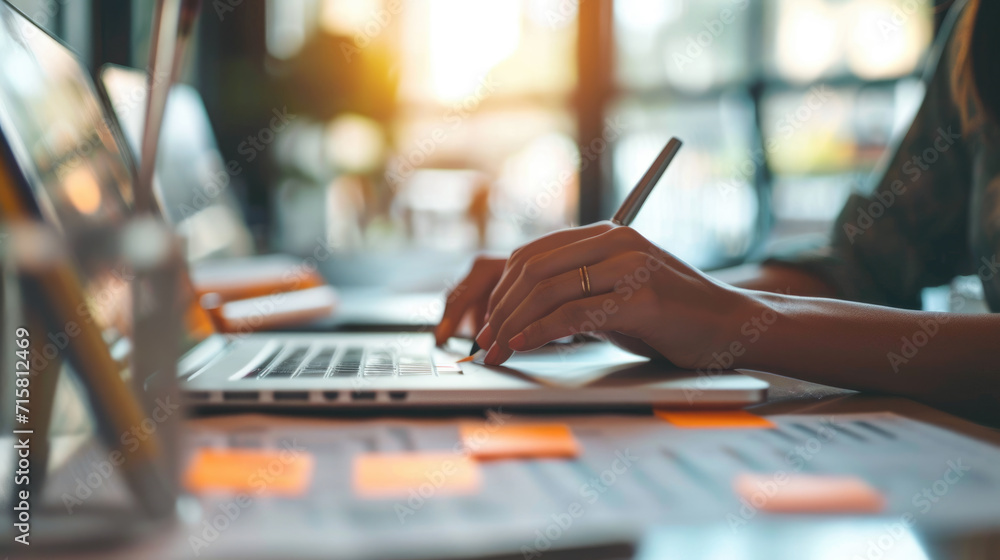 Poster hands of a person typing on a laptop keyboard with a blurred background of stacked files and documen