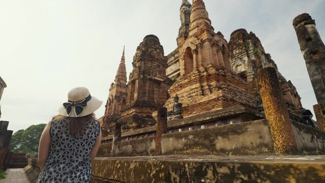 Ancient sites, tourist attractions in Sukhothai, Thailand. Rear view of tourist woman walking into Wat Mahatat temple, Sukhothai historical park, Sukhothai, Thailand. UNESCO World heritage site