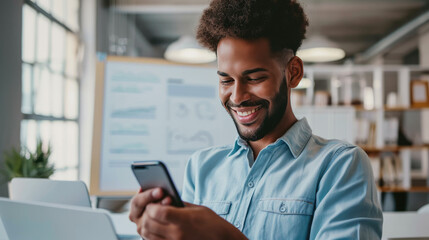 Happy man using a smartphone during his work in the office