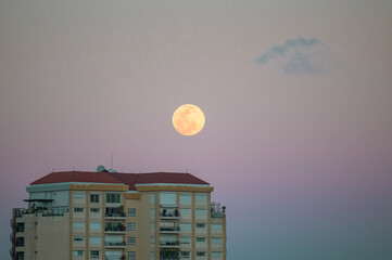 full moon rising over building
