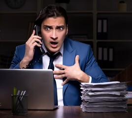 Young male employee working night in the office