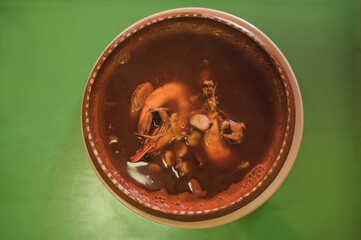 Seafood soup with shrimp, octopus, oyster, fish, with chilies, onion and cilantro, served on a clay...