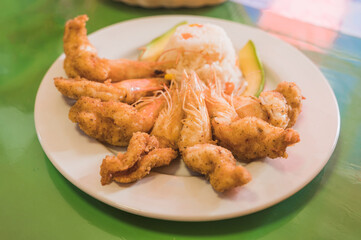Breaded shrimp, accompanied with white rice, and avocado.