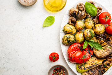 Grilled vegetables and mushrooms on plate over white background, top view