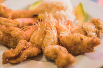 Breaded shrimp, accompanied with white rice, and avocado.