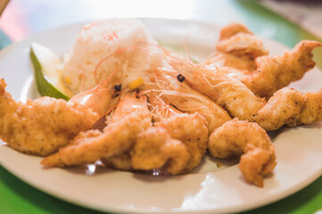 Breaded shrimp, accompanied with white rice, and avocado.