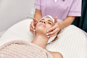 Beautiful woman getting face massage treatment in beauty salon. Skin care.