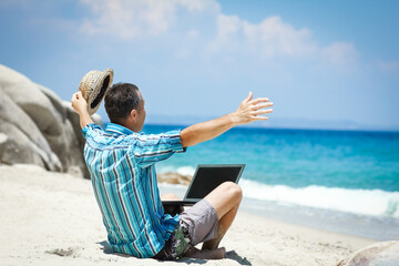 A Happy man guy with laptop near the seashore weekend travel