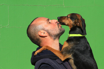 Hundeliebe - Mann mit Hund vor grüner Wand