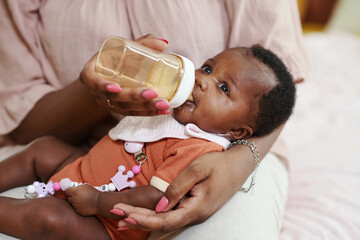 Black woman feeding her newborn baby girl with formula - obrazy, fototapety, plakaty