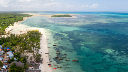 Aerial view of the fishing boats on tropical sea coast with sandy beach.Summer travel in Zanzibar, Africa. Top view of boats, yachts and clear blue water.